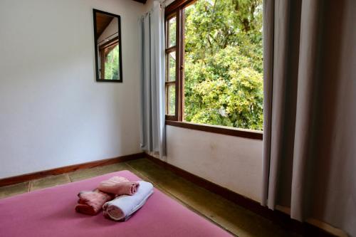 een bed met een roze deken in een kamer met een raam bij Casa Matatiso - quartos privados em casa compartilhada in Abraão