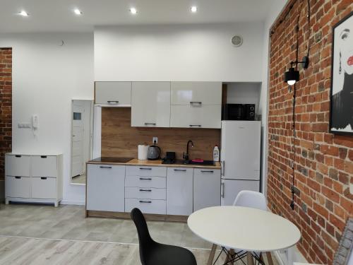a kitchen with white cabinets and a brick wall at Konopnickiej 9 Apartament Loft dostęp na kod in Pabianice