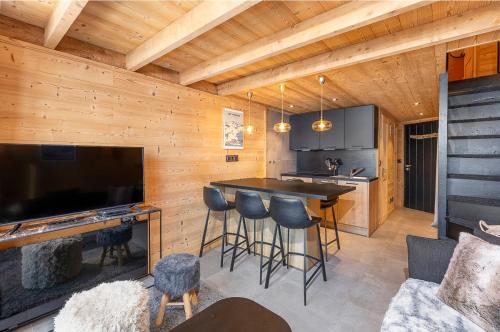 a kitchen with a bar with stools and a television at Val Thorens - Cosy Duplex avec Vue Pied des pistes Silveralp 570 in Val Thorens