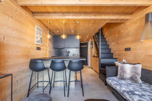 a kitchen with a bar with stools in a cabin at Val Thorens - Cosy Duplex avec Vue Pied des pistes Silveralp 570 in Val Thorens