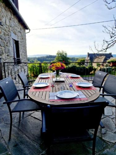 - une table en bois avec des assiettes et des fleurs sur la terrasse dans l'établissement Le Casimir, Maison de campagne à Estaing, à Estaing
