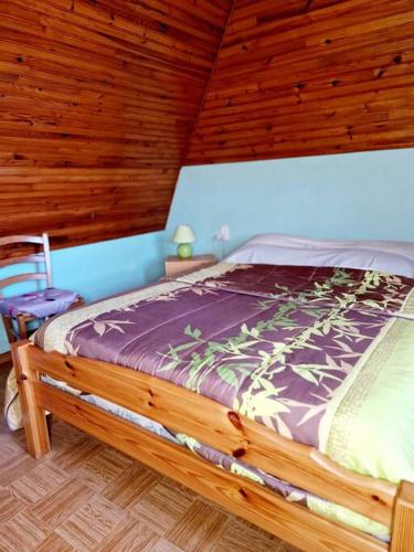 un lit dans une chambre avec un plafond en bois dans l'établissement Le Casimir, Maison de campagne à Estaing, à Estaing