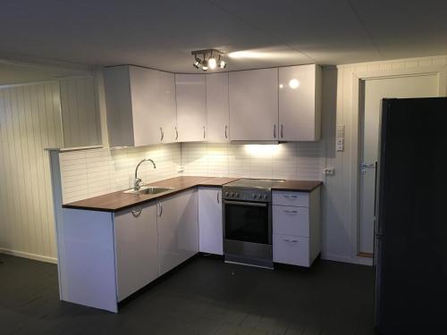 an empty kitchen with white cabinets and a sink at Sentralt plassert leilighet ved Sherpatrappen in Tromsø