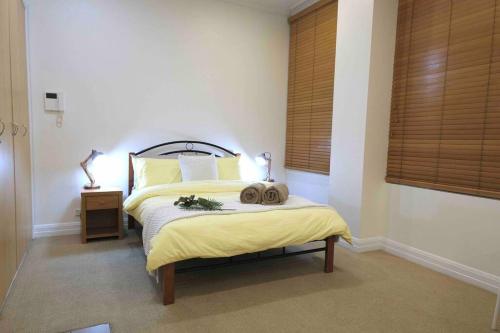 een slaapkamer met een bed met een gele deken bij Comfortable City Apartment *Wi-Fi* in Melbourne