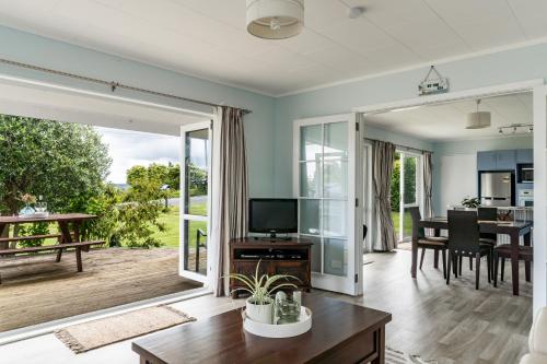 a living room with a television and a table at Calypso Cottage in Raglan