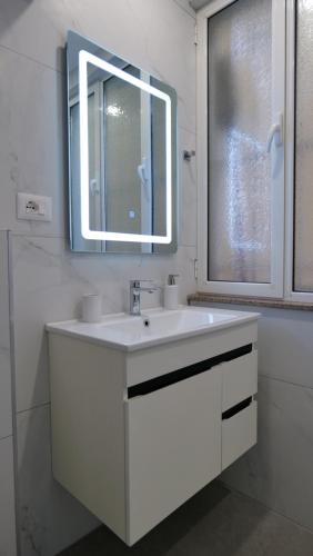 uma casa de banho branca com um lavatório e um espelho em Kristi Apartments 02 em Tirana