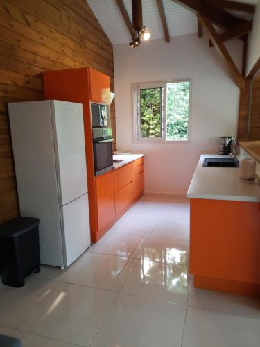 una cucina con un frigorifero bianco e mobili arancioni di Cottages Les Ventilés a Deshaies