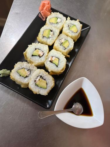 a black plate of sushi with a bowl of dipping sauce at Hostal agripino y Restaurante asiático in Mora