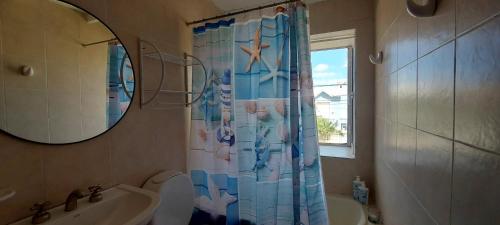a bathroom with a sink and a shower curtain at Las Grutas Star in Las Grutas