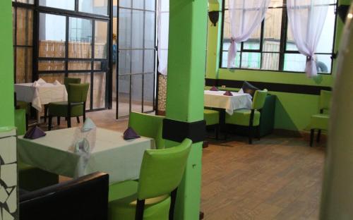um restaurante com mesas e cadeiras e paredes verdes em ASARAG em Mirleft