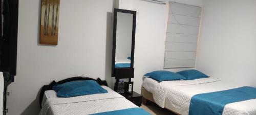 a bedroom with two beds with blue pillows and a mirror at Hotel Mykonos Manta in Manta