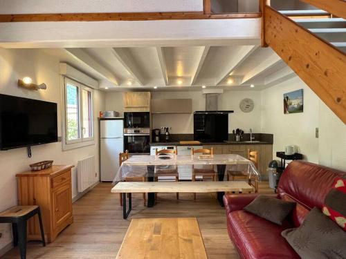 a living room with a table and a kitchen at Le 101 Chalet 3 chambres Terrasse Parking in Cauterets