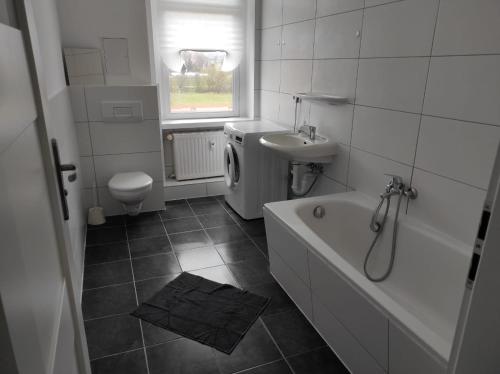 a bathroom with a tub and a sink and a toilet at Furnished apartments for employees with separate rooms in Zeitz