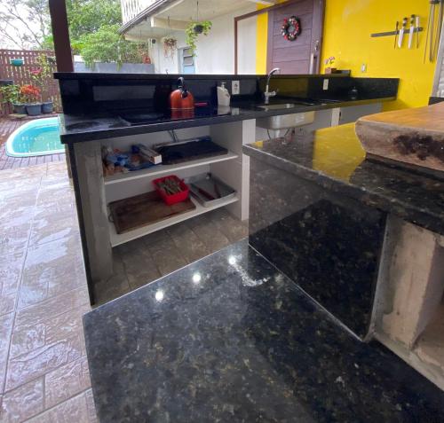 a kitchen with a black counter top and a pool at Paraíso do santinho in Florianópolis
