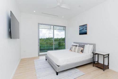 a white bedroom with a bed and a window at ONE Canal Point in Upper Land