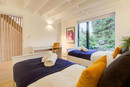 a bedroom with two beds and a large window at Neoteric Home Wimbledon Village in London
