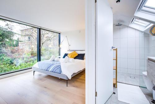 a bedroom with a bed and a large window at Neoteric Home Wimbledon Village in London