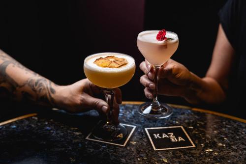 two people holding cocktails on a table at Ovolo The Valley Brisbane in Brisbane