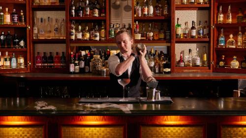 a man standing at a bar with a glass of wine at Ovolo The Valley Brisbane in Brisbane