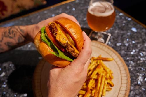 a person holding a sandwich with a plate of fries at Ovolo The Valley Brisbane in Brisbane