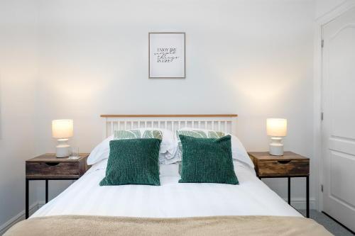 a bedroom with a white bed with green pillows at Entire House in Ipswich in Ipswich