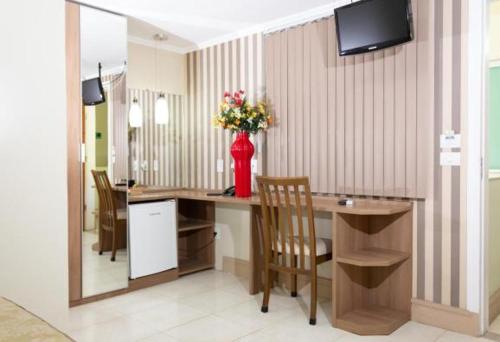 a room with a desk with a vase of flowers on it at Hotel Cravo e Canela in Campos dos Goytacazes
