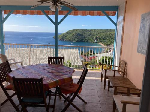 a table and chairs on a balcony with a view of the ocean at Caraïbe in Les Anses-dʼArlets