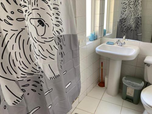 a bathroom with a zebra shower curtain and a sink at DEPARTAMENTO MARAVILLOSA VISTA A JARDINES BAHIA PELICANOS in Puchuncaví