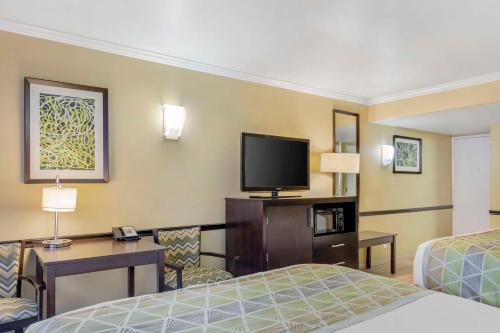 a hotel room with two beds and a flat screen tv at Best Western Canoga Park Motor Inn in Canoga Park