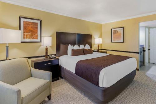 ein Hotelzimmer mit einem großen Bett und einem Stuhl in der Unterkunft Best Western Canoga Park Motor Inn in Canoga Park