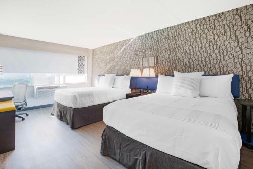 ein Hotelzimmer mit 2 Betten und einem Schreibtisch in der Unterkunft GLō Best Western Mississauga Corporate Centre in Mississauga