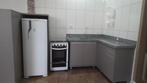 a small kitchen with a refrigerator and a stove at Recanto da Lagoa in Passo de Torres
