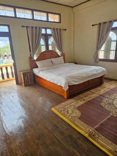 a bedroom with a large bed in a room with windows at Kai Lions International Hostel in Paksong