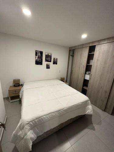een slaapkamer met een groot wit bed in een kamer bij Apartamento en el poblado vista a todo Medellín. in Medellín