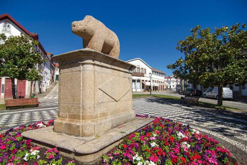 una estatua de un oso en un pedestal de flores en Casa da Praça de Murça, en Murça