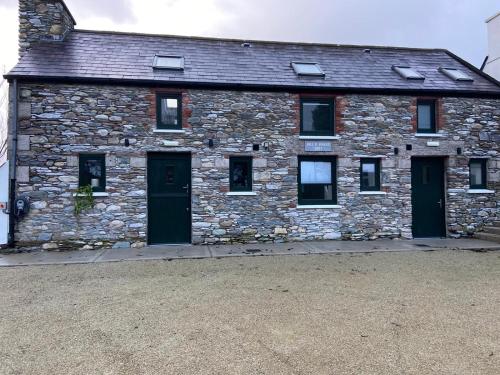 an old stone building with two doors and windows at Bill's Barns, Apartment 1 in Kenmare