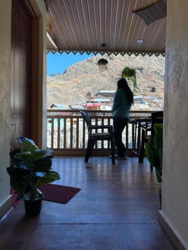 a woman sitting at a table on a porch at Laxmi Narayan Homestay-Harshil in Harsil