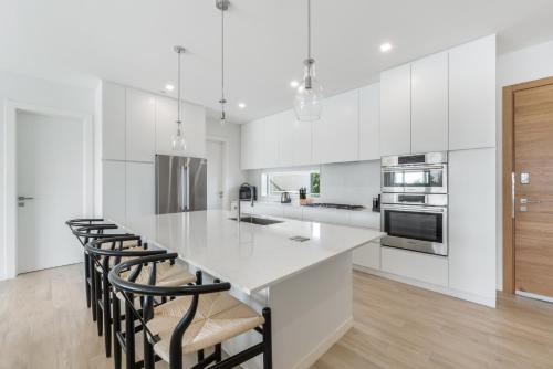 a kitchen with white cabinets and a large island with bar stools at ONE Canal Point in Upper Land