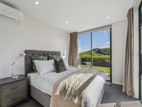 a bedroom with a bed and a large window at Hawthorne House in Queenstown
