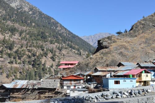a village on a hill with mountains in the background at Laxmi Narayan Homestay-Harshil in Harsil