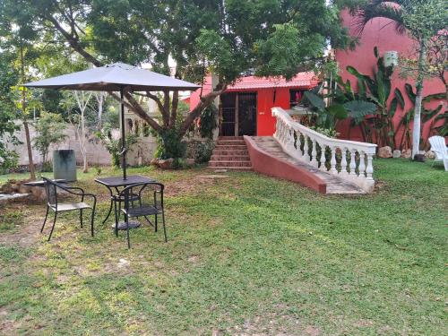 a table and chairs and an umbrella in a yard at Villa lirios in Valladolid