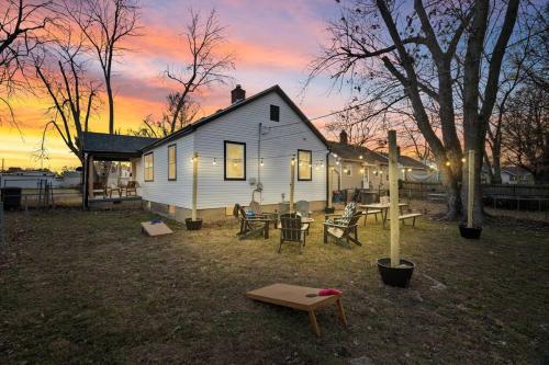 a white house with a picnic table and a sunset at Urban Oasis Cozy Home Near Downtown with Game Room and Firepit in Evansville