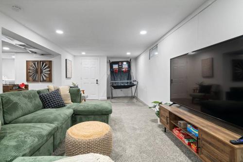 a living room with a couch and a flat screen tv at Urban Oasis Cozy Home Near Downtown with Game Room and Firepit in Evansville