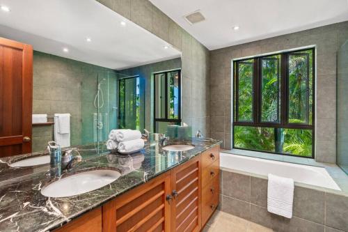 Barong Luxury Home overlooking Cairns Unrivalled privacy and location في كيرنز: حمام به مغسلتين وحوض استحمام ونافذة