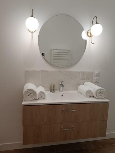 a bathroom with a sink with a mirror and towels at Clos de la Providence Chambres d'hôtes, piscine et Spa in Nolay