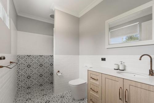 La salle de bains blanche est pourvue de toilettes et d'un lavabo. dans l'établissement 35 Newland St Victor Harbor, à Victor Harbor