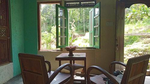 a room with a table and chairs and windows at duegoal farmhouse in Jatiluwih