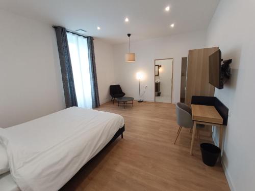 a bedroom with a bed and a desk and a television at Clos de la Providence Chambres d'hôtes, piscine et Spa in Nolay