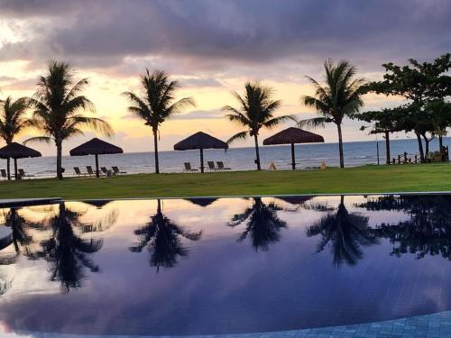 una piscina con palmeras y el océano en Apto completo para curtir uma boa praia e relaxar, en Camassari
