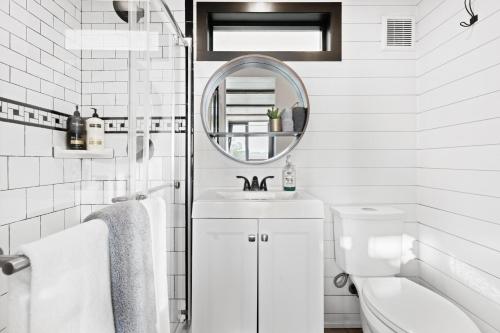 Baño blanco con lavabo y espejo en Tiny Cargo Home North, en Tulare
